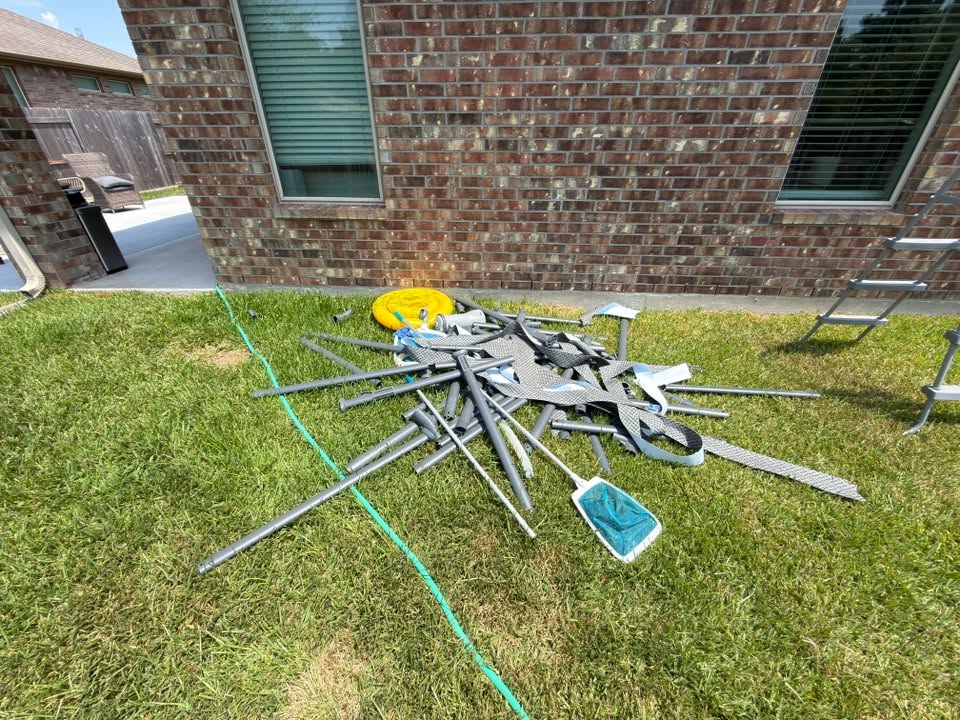 Back yard piled with a dismantled metal frame before Thompson Disposal Services hauled it away
